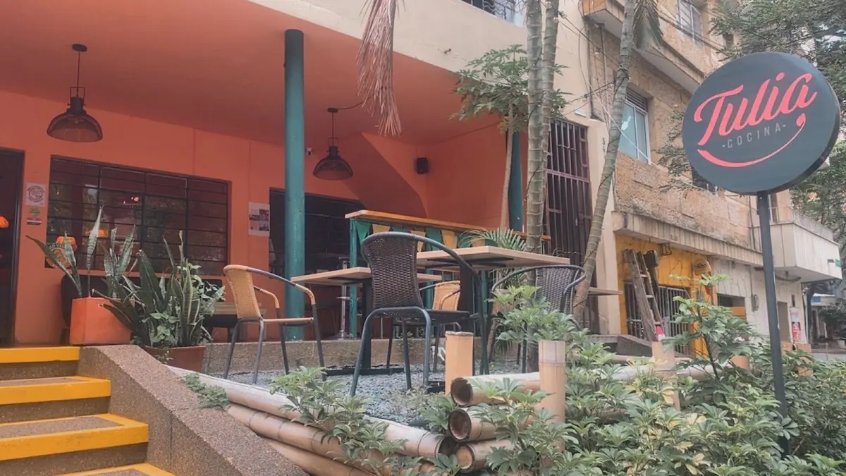 Fachada de Tulia Cocina con su terraza, plantas y el aviso redondo del restaurante