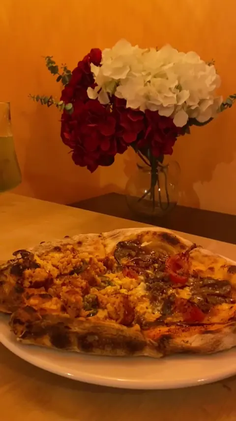 Pizza servida en una mesa con flores