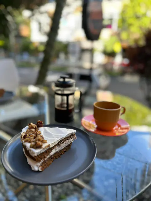 Porción de torta de zanahoria y café en prensa francesa en la terraza